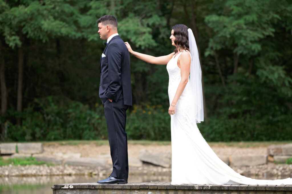 bride and groom at dock on pond