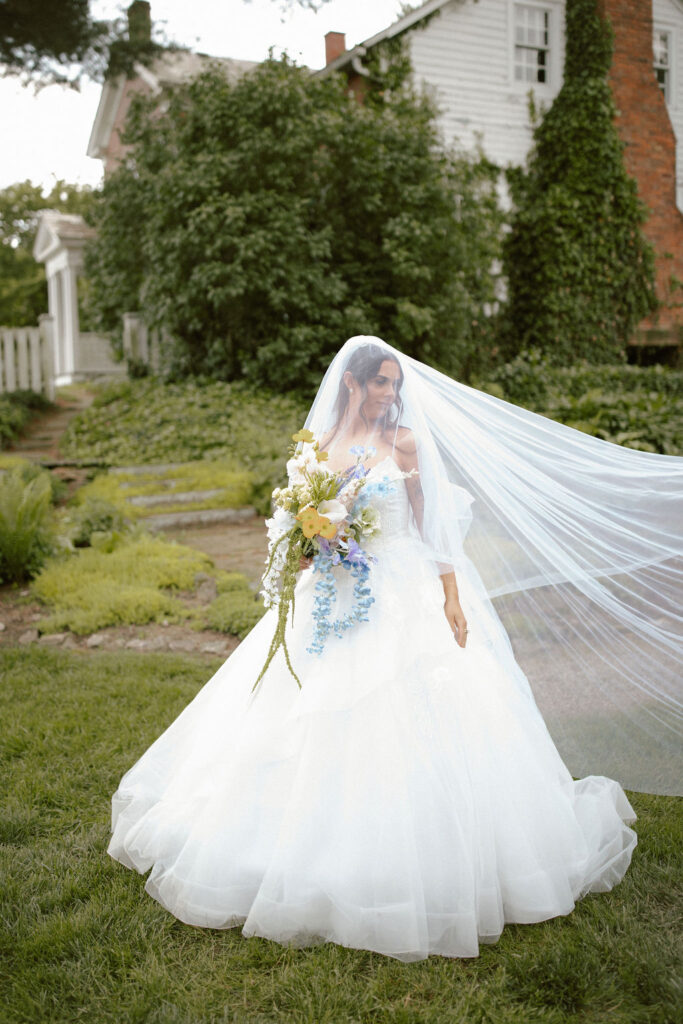 bride with long veil at farmhouse with gardens