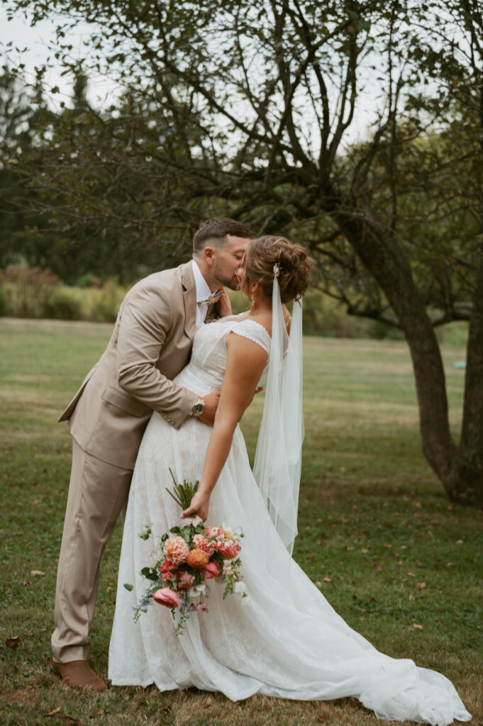 bride and groom kissing in apple orchard