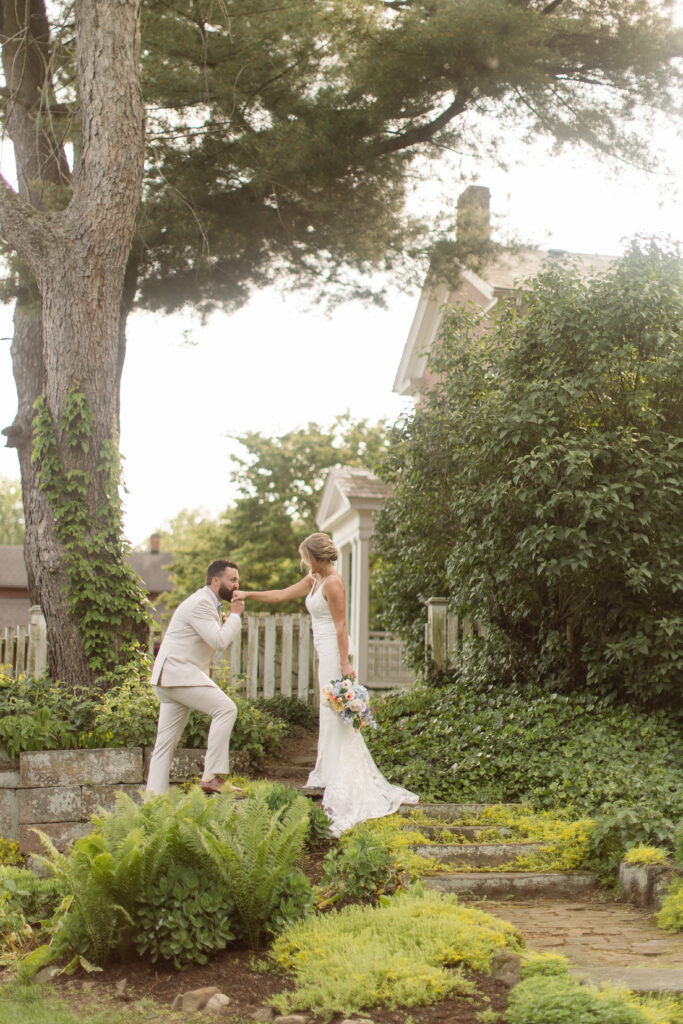 groom kissing bride's hand at garden